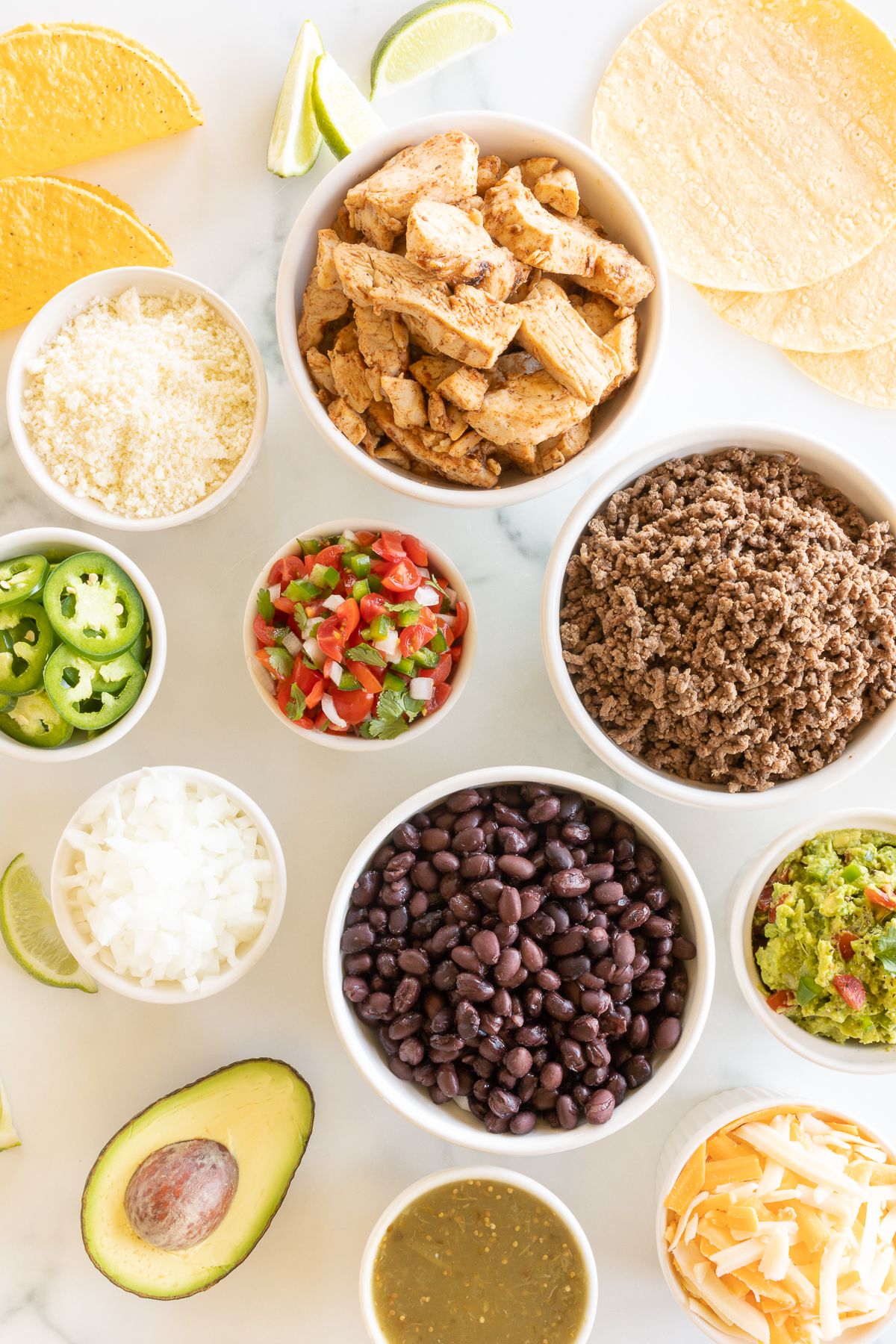 A display of taco toppings on a white marble countertop