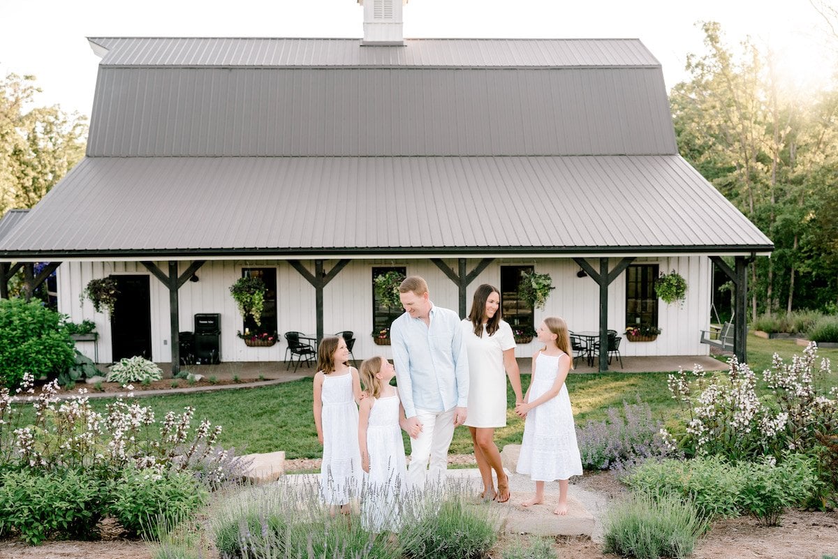 Lifestyle Gleam and family in front of white farmhouse