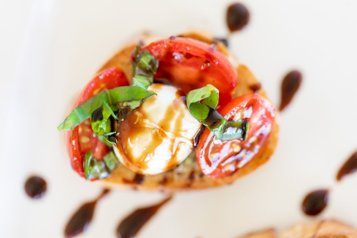 Bruschetta with mozzarella on crostini, on a white platter