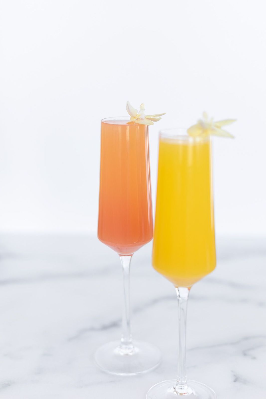 A grapefruit paloma on a gold bar cart, white tulips and fresh juices in the background