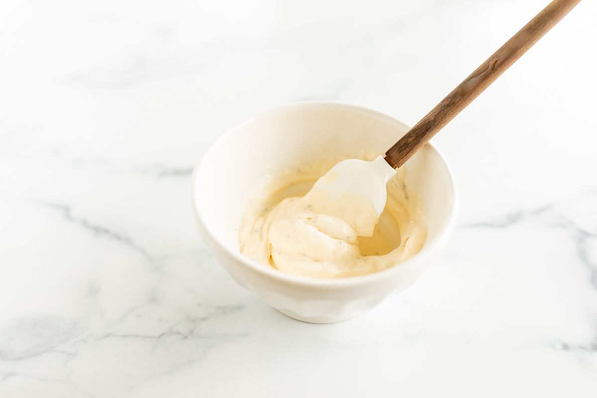 A small white bowl full of mayonnaise.