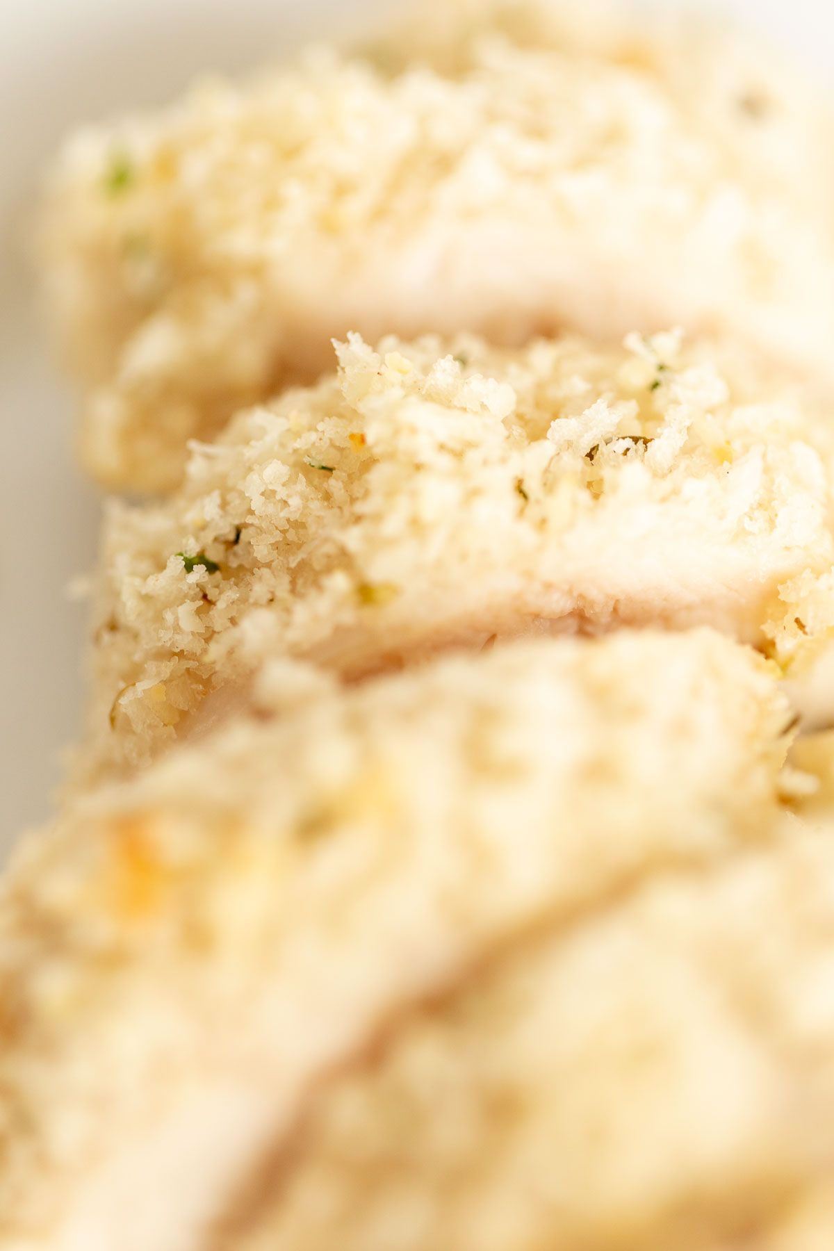 A white platter with panko breaded chicken, sliced lemon for garnish