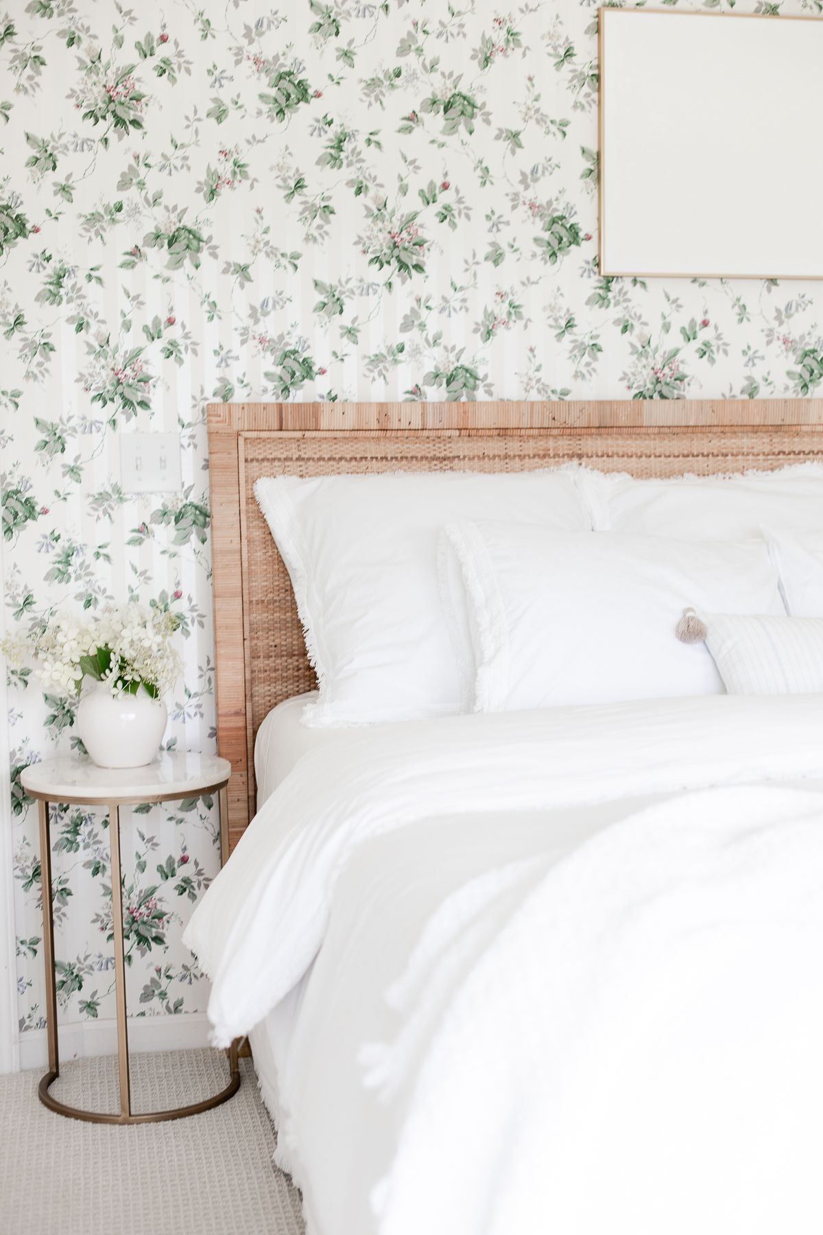 A wallpapered bedroom with plaster canvas art over the bed