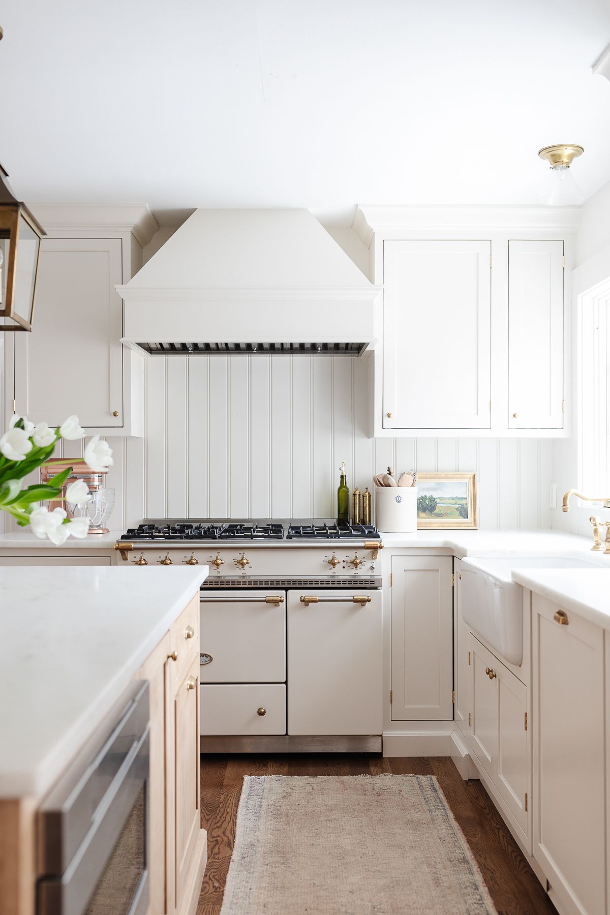 A cream kitchen with a traditional rug on the hardwood floors