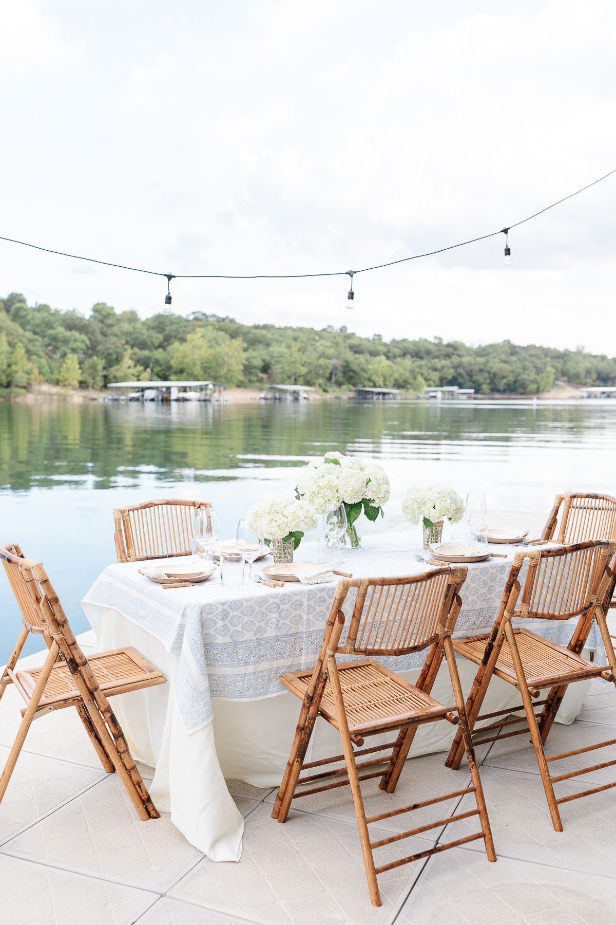 An outdoor dining table set up with string lights above