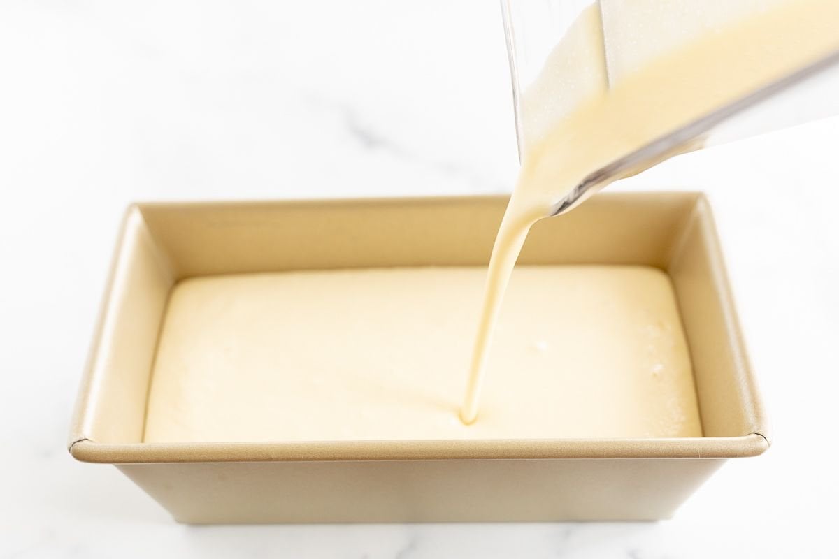 Liquid orange sherbet pouring into a loaf pan before freezing