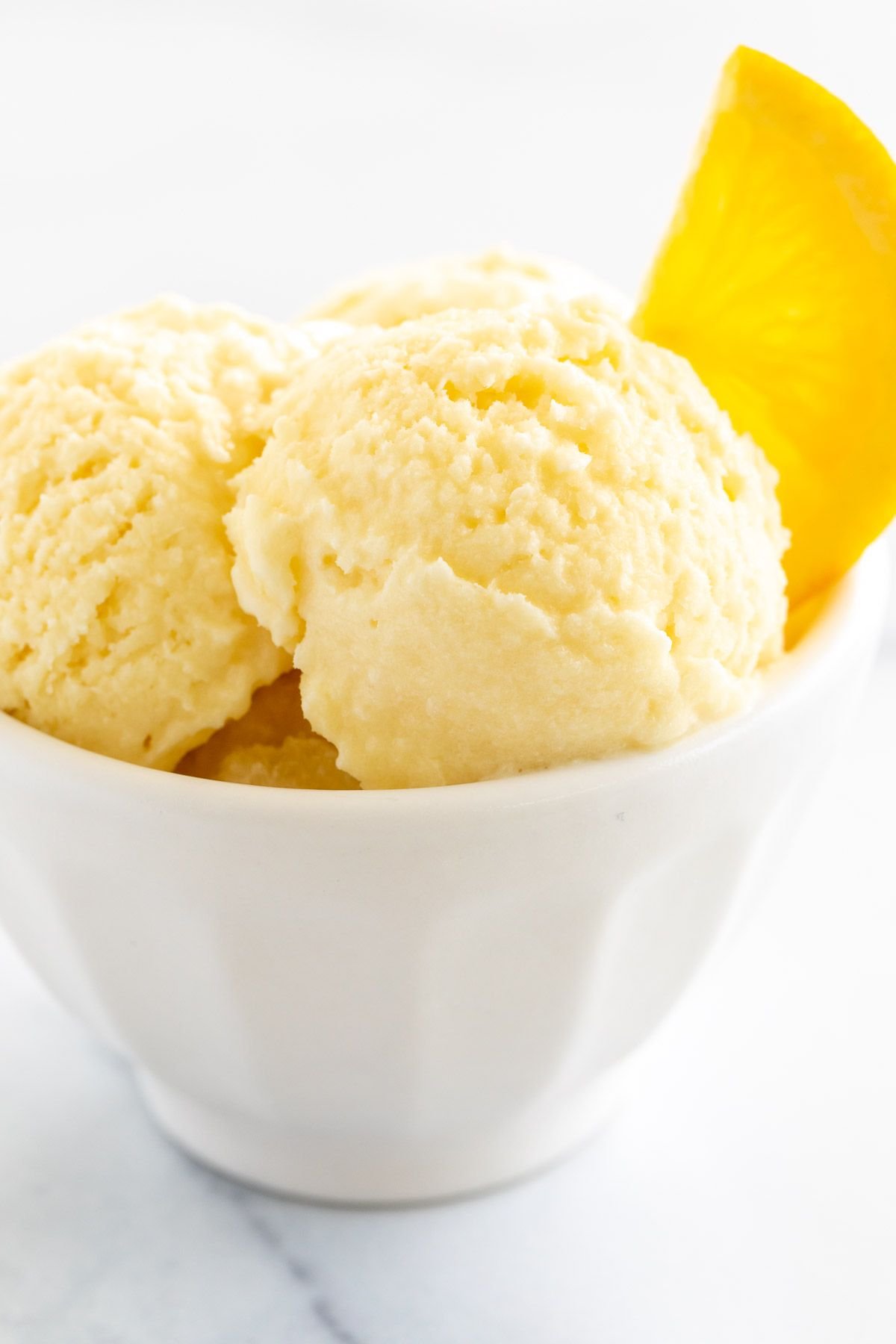 orange sherbet garnished with a slice of orange in a white bowl