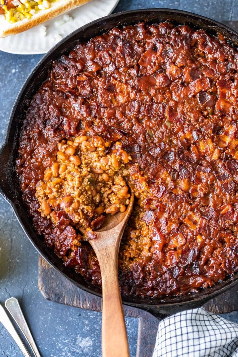 a cast iron skillet with bbq beans and a wooden sppon