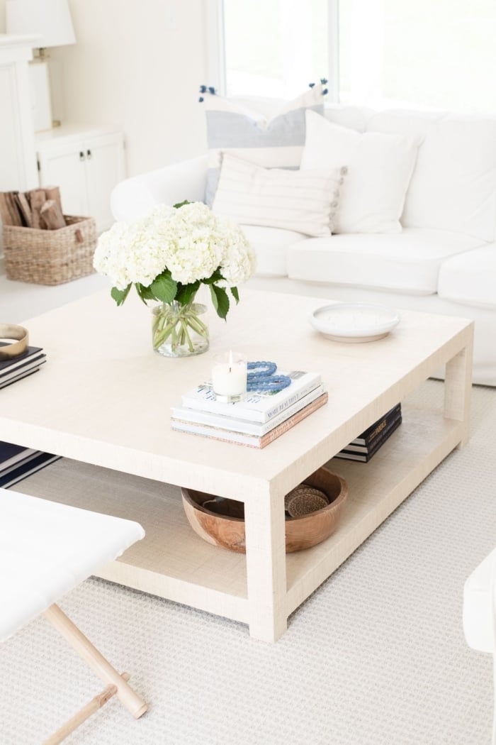 A white living room with coastal accents and blue and white coffee table decor.