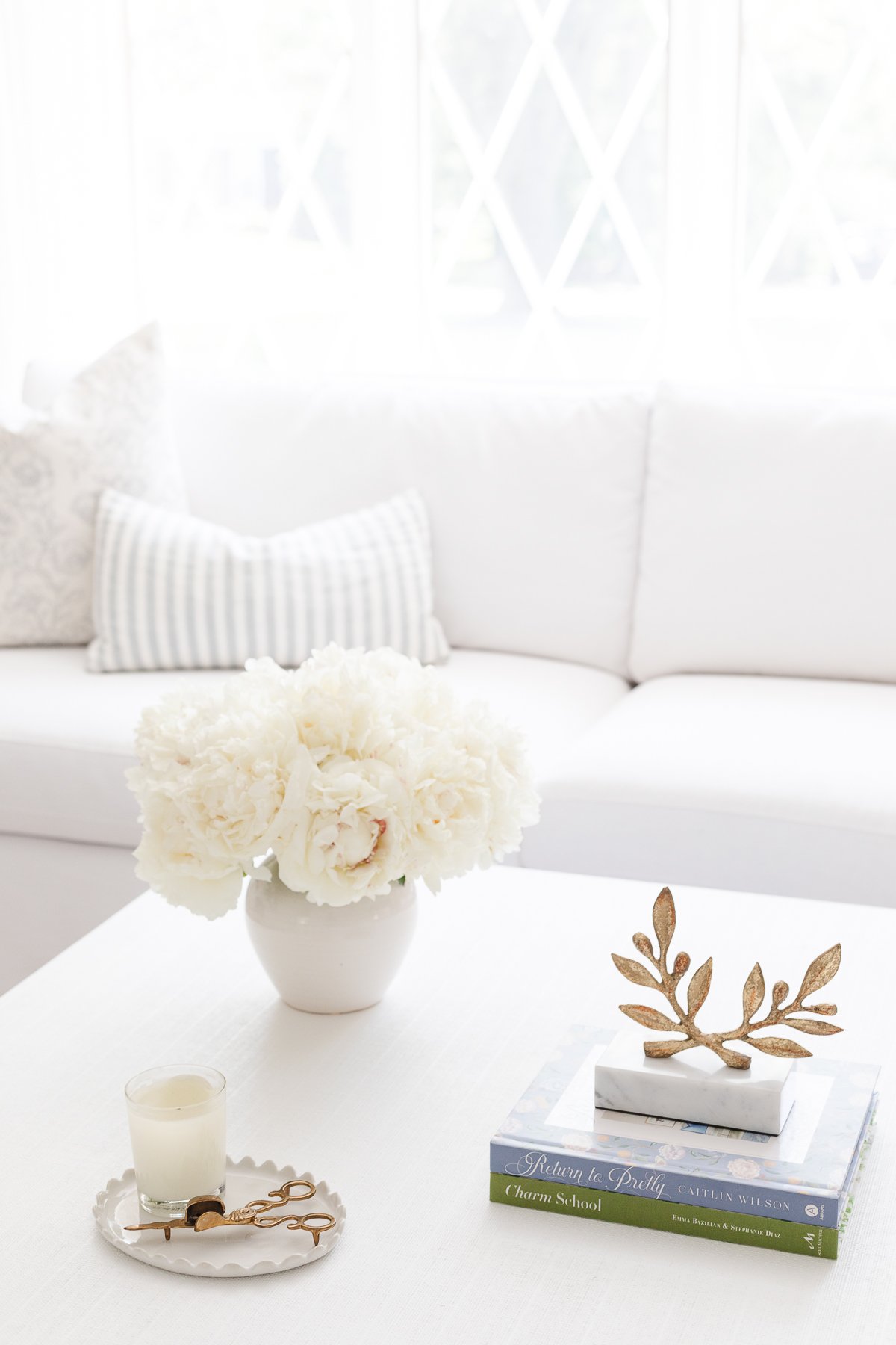 A white coffee table with soft blue and white coffee table decor.