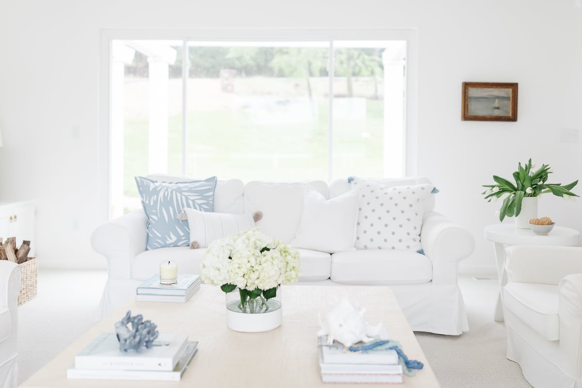 A white coffee table with soft blue and white coffee table decor.