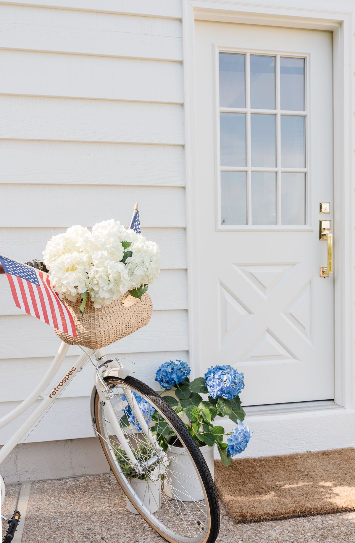 A white biked parked in front of a white door with a brass exterior door handle