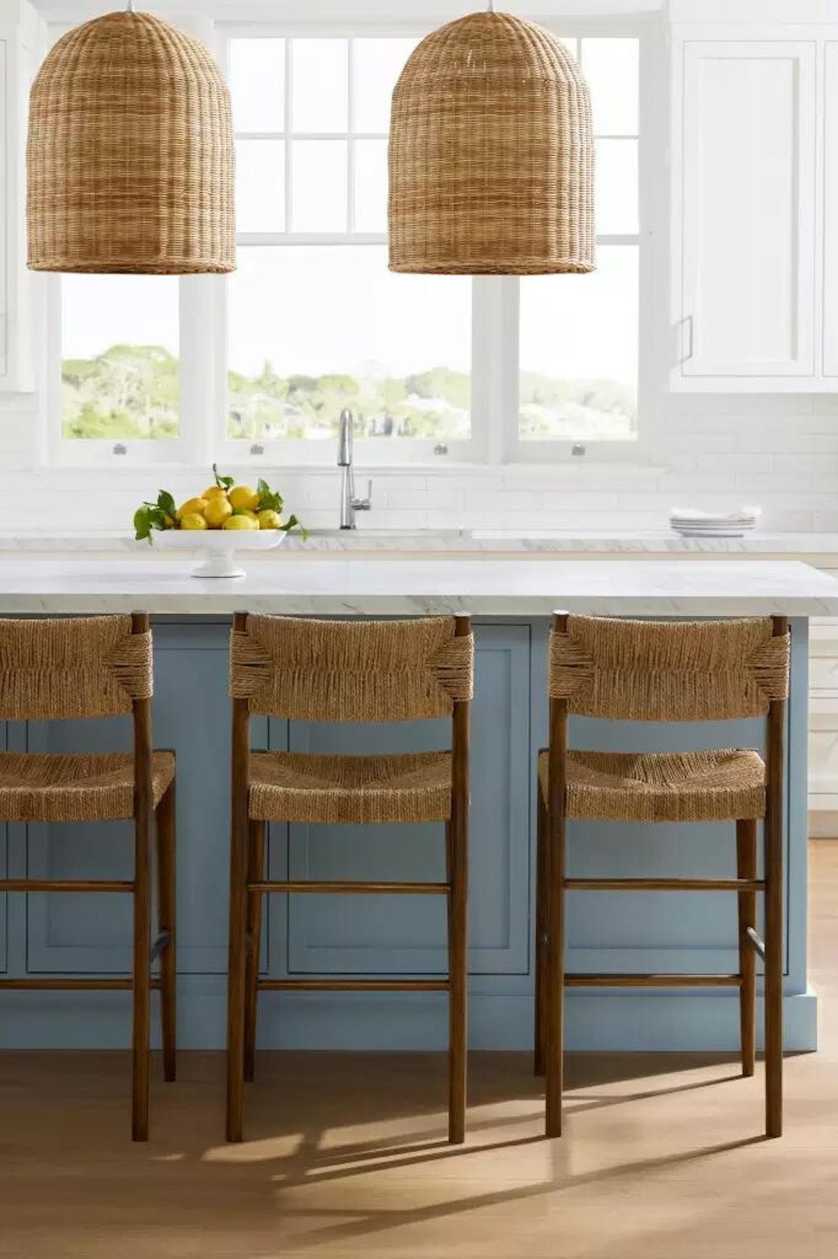 Three rattan bar stools in a blue kitchen.