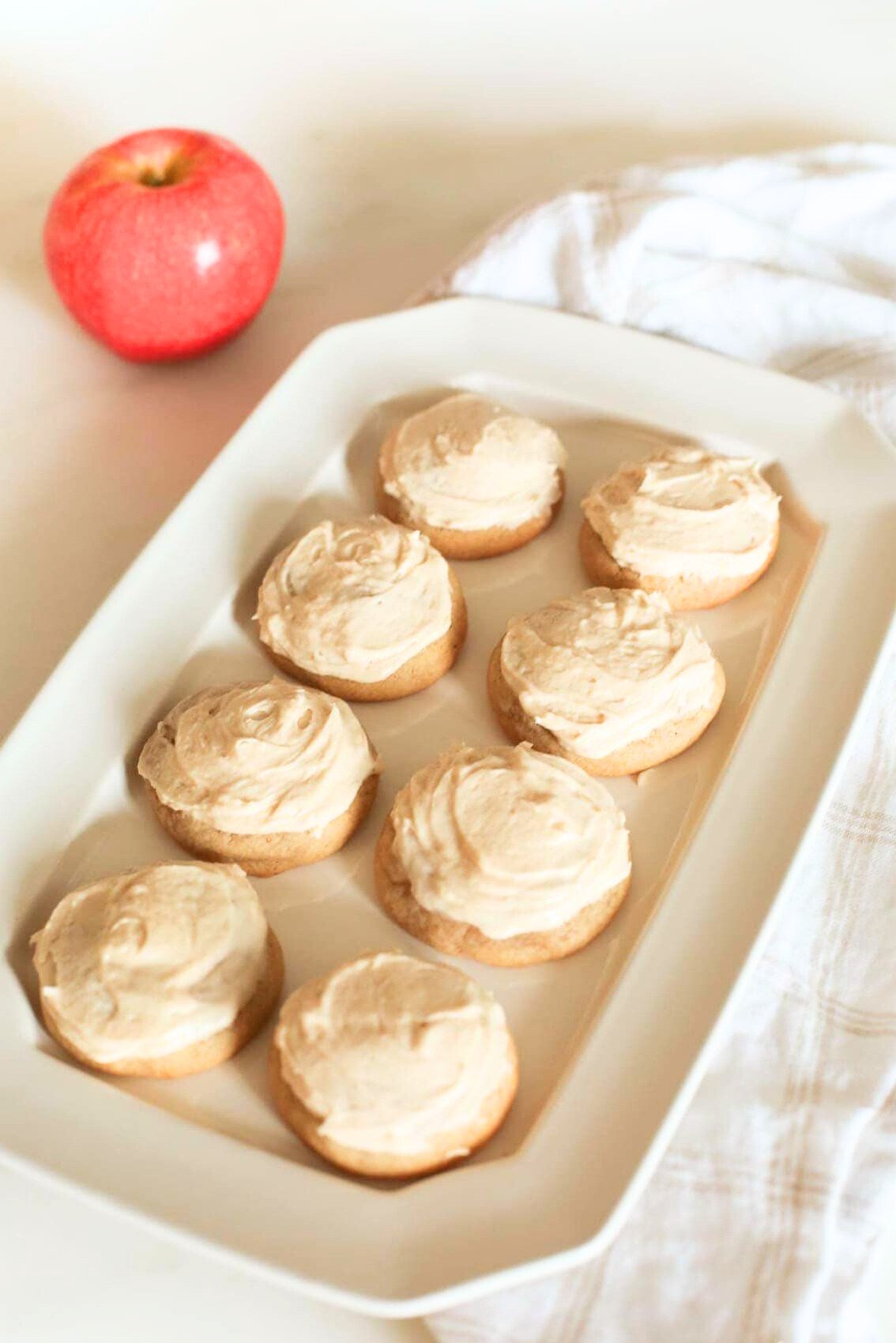 A plate of cookies with icing, adorned with a delicious apple.