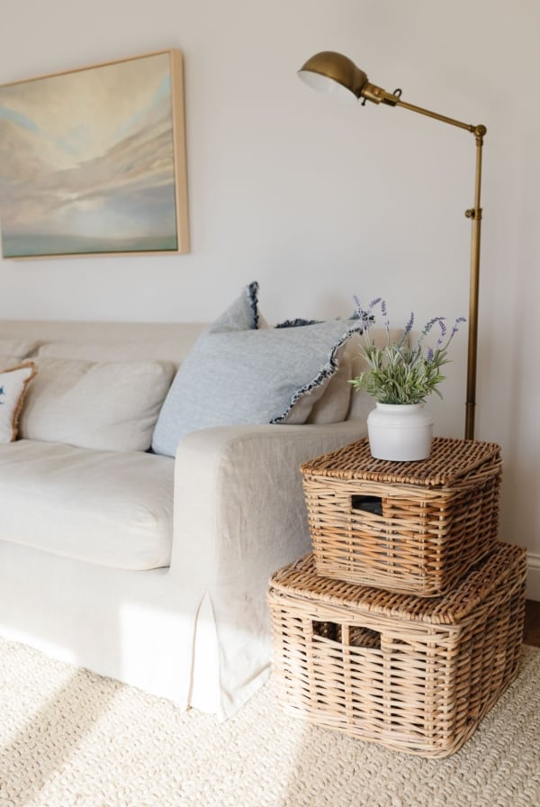 A restoration hardware linen sofa with stacked baskets as side tables