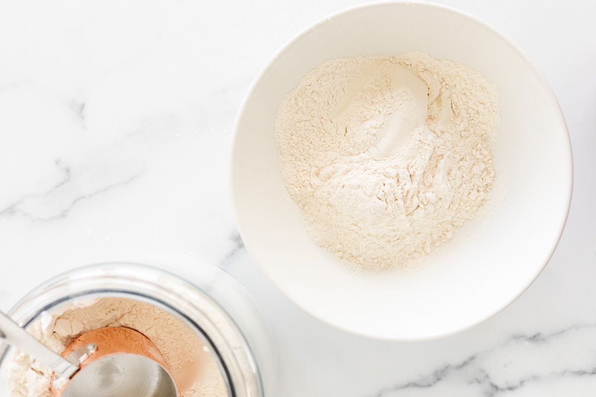 A white bowl full of flour on a marble surface