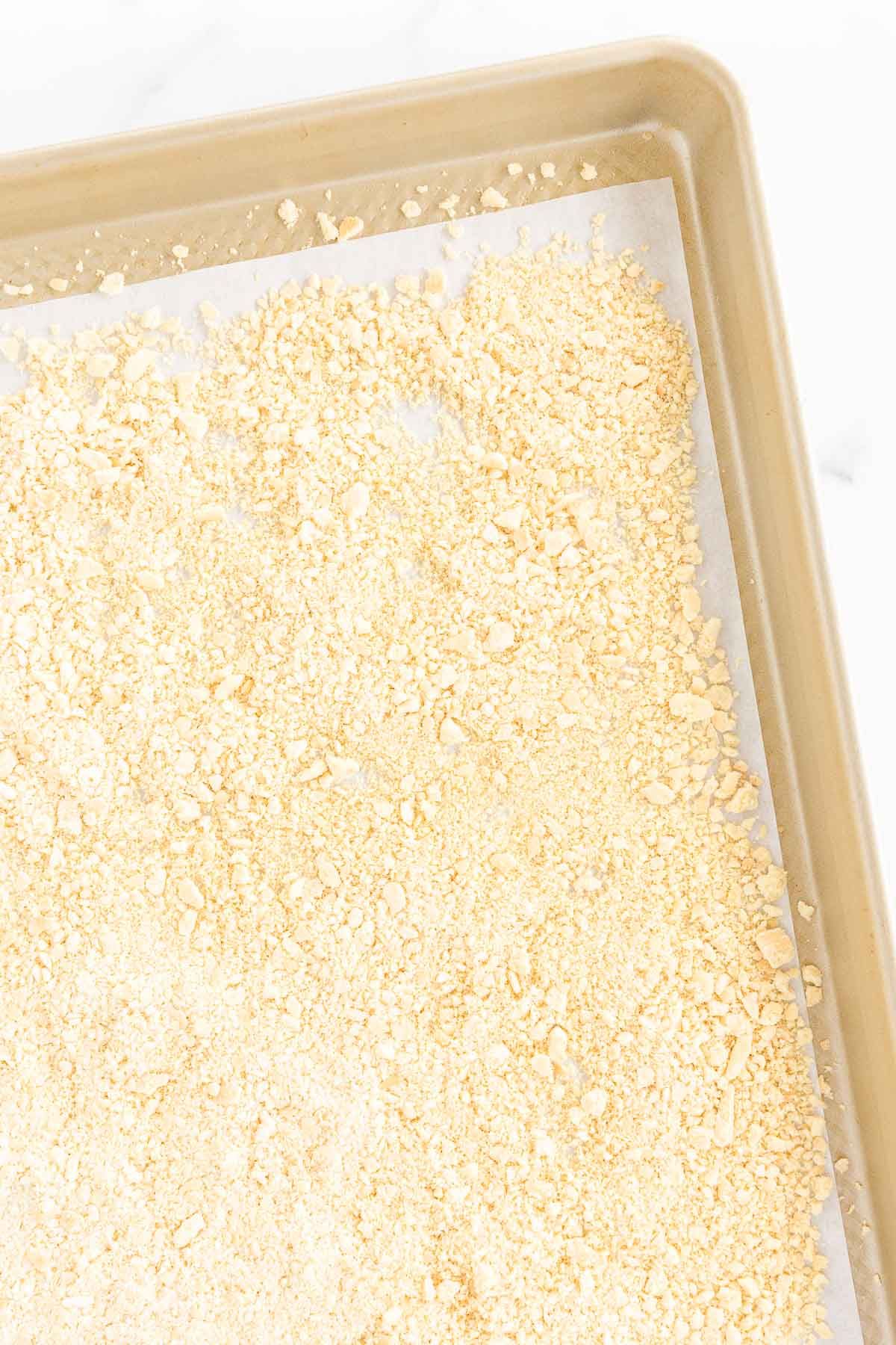 A panko substitute breadcrumb on a gold baking sheet lined with parchment paper