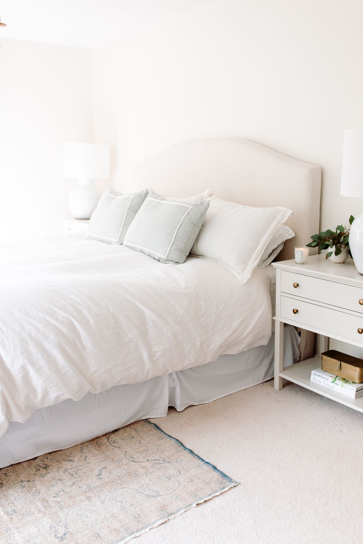 A white bedroom with a vintage rug on carpet