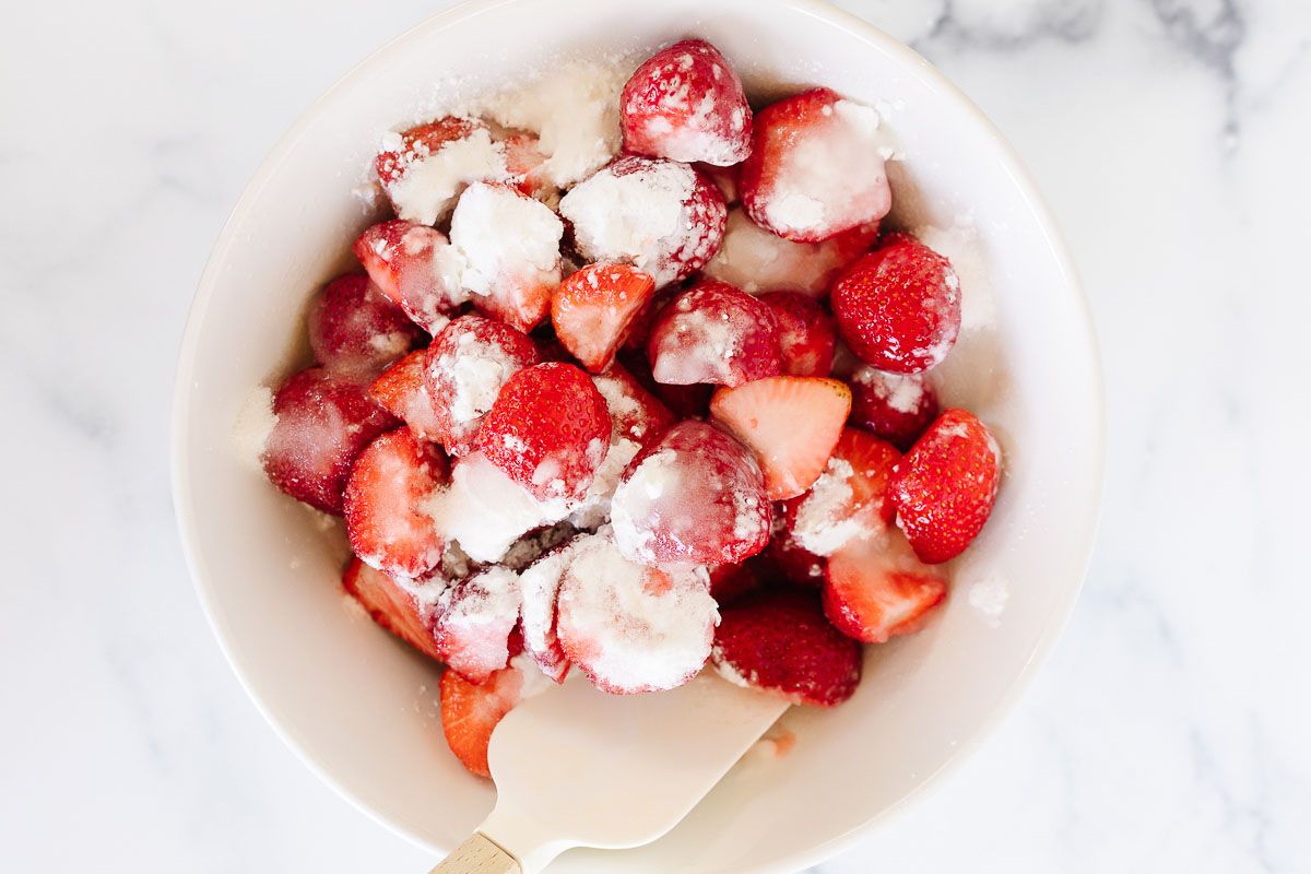 The filling of a strawberry crumble, in a white mixing bowl