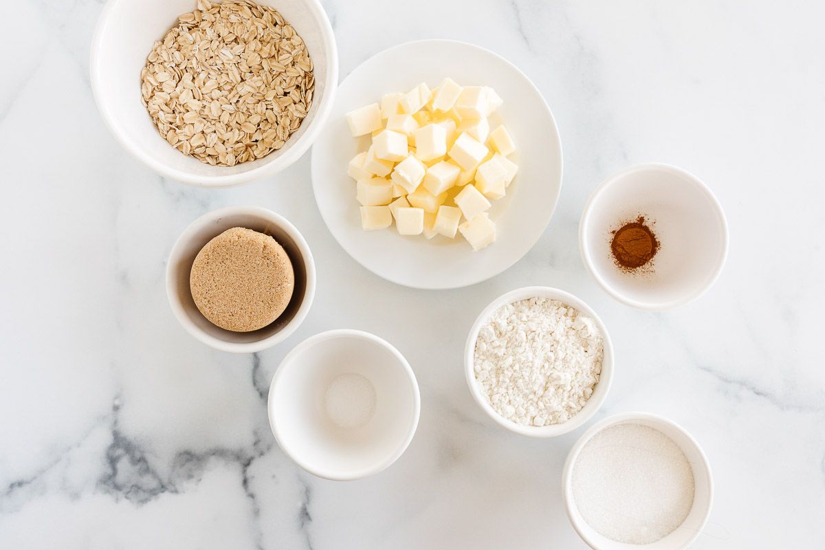 Strawberry crumble topping ingredients laid out in white bowls on a marble surface