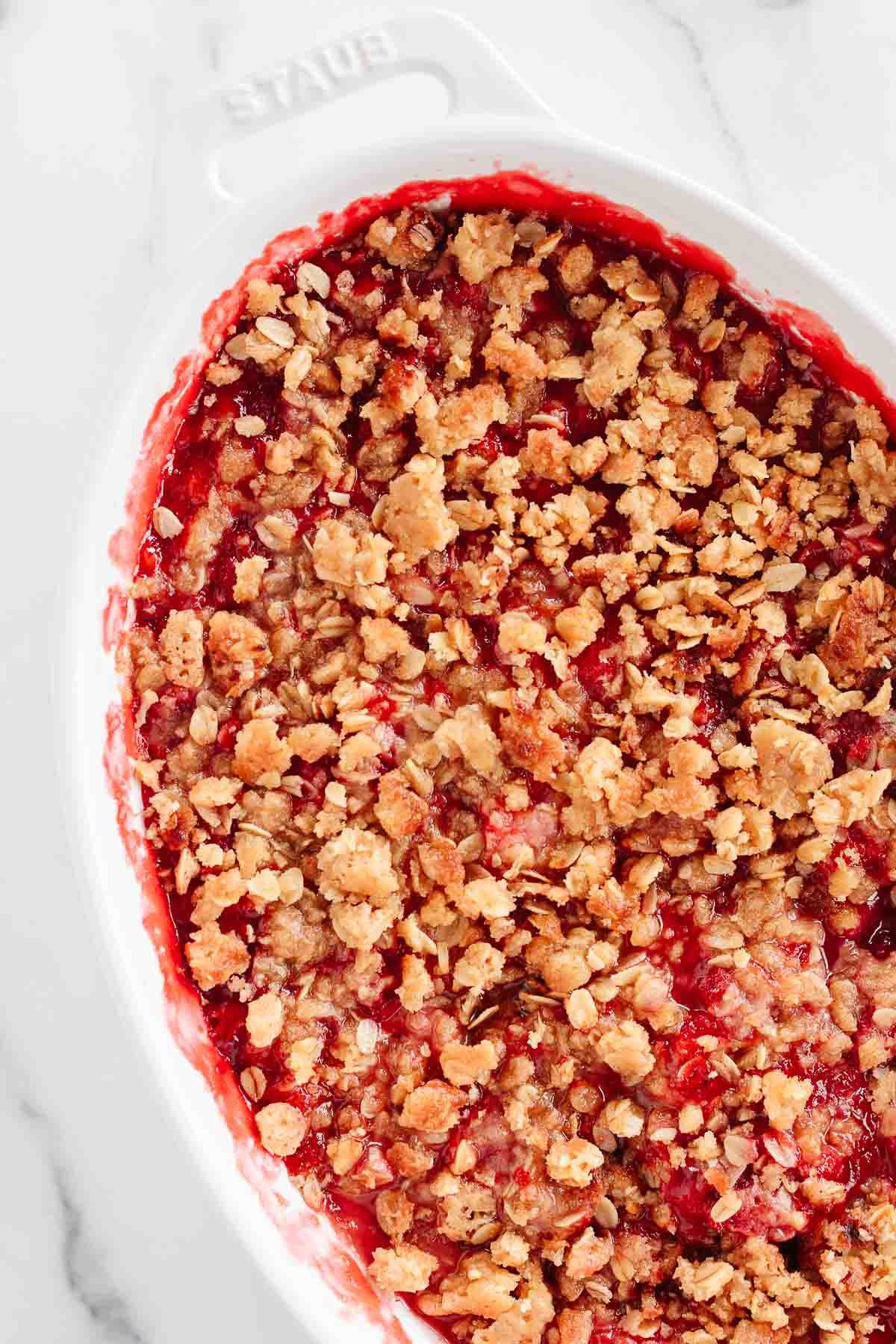 A strawberry crumble in a white oval baking dish