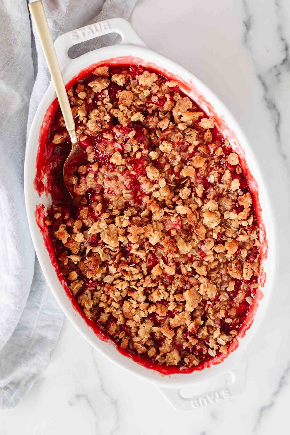 A strawberry crumble in a white oval baking dish