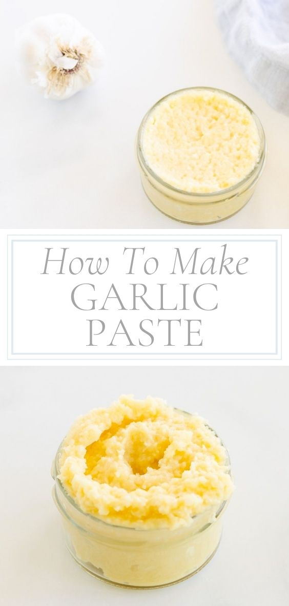 On a marble counter top there is a clear glass jar of garlic paste, a whole head of garlic, and a grey napkin.
