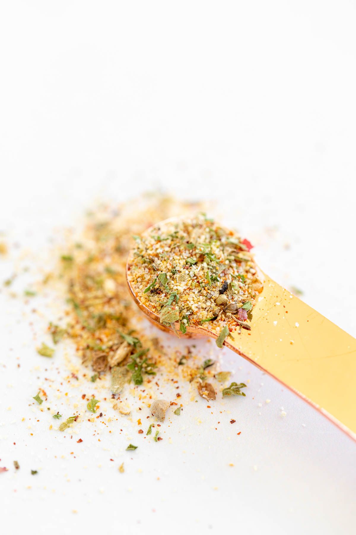 A copper teaspoon placed on a marble countertop, with all purpose seasoning.