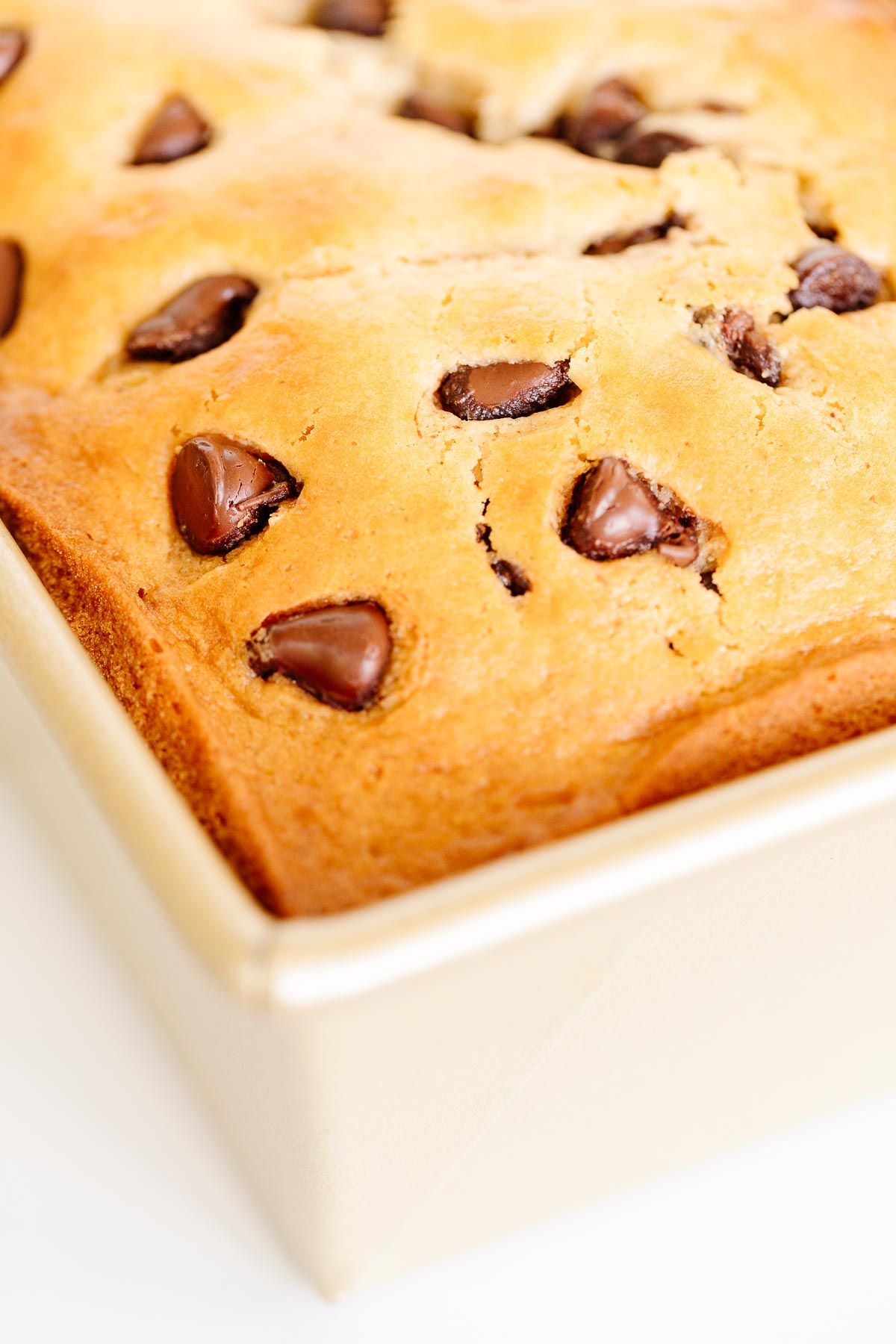 A chocolate chip loaf inside a gold loaf pan.