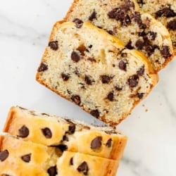 A chocolate chip bread loaf on a marble countertop, sliced for serving.