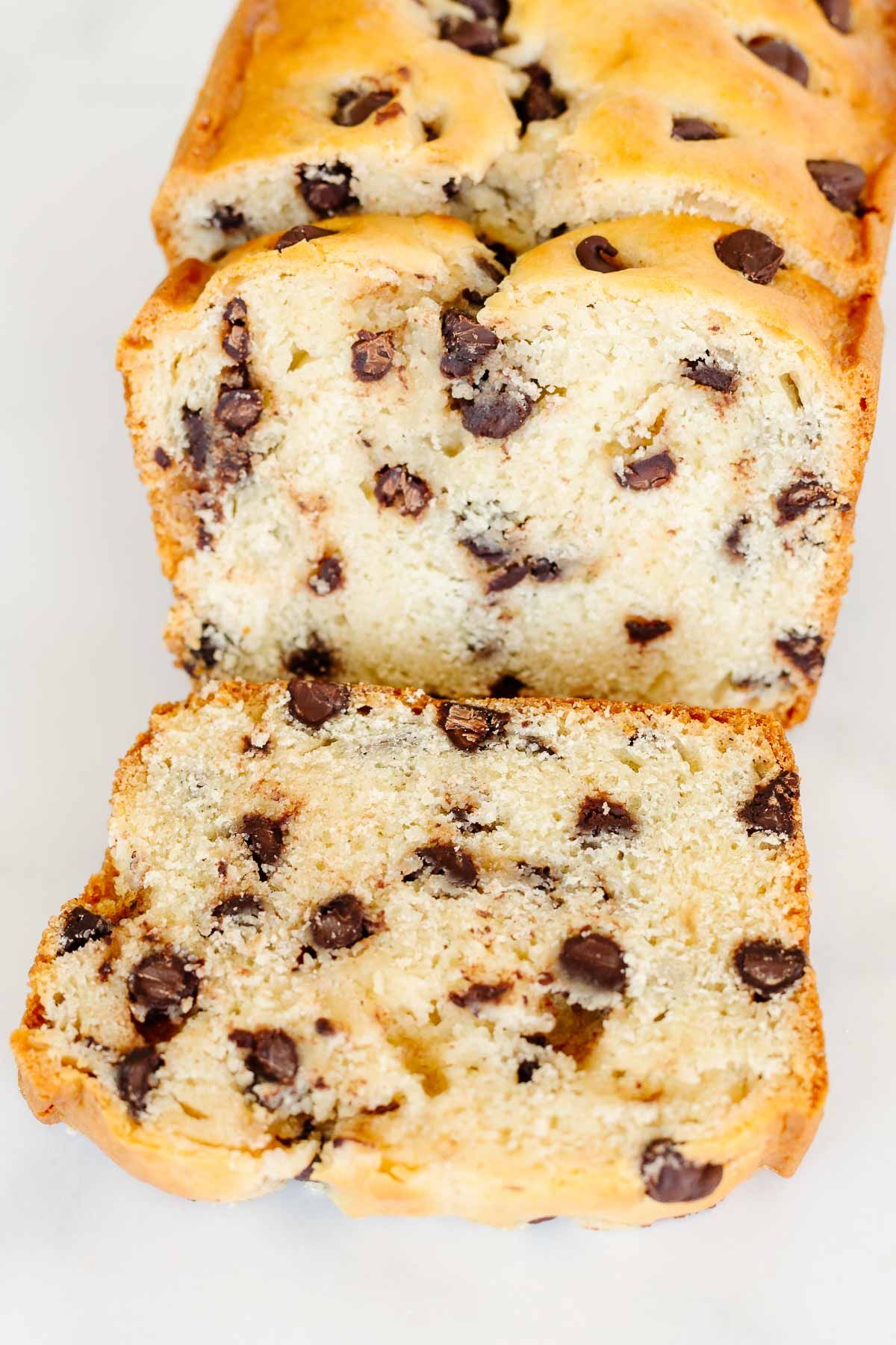 A chocolate chip bread loaf on a marble countertop, sliced for serving.