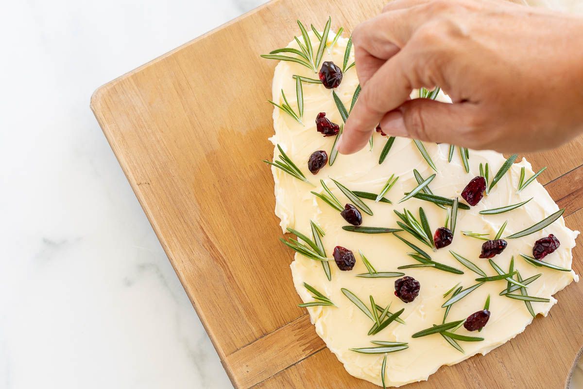 A Christmas butter board, placed on a wooden charcuterie board and shaped into a Christmas tree.