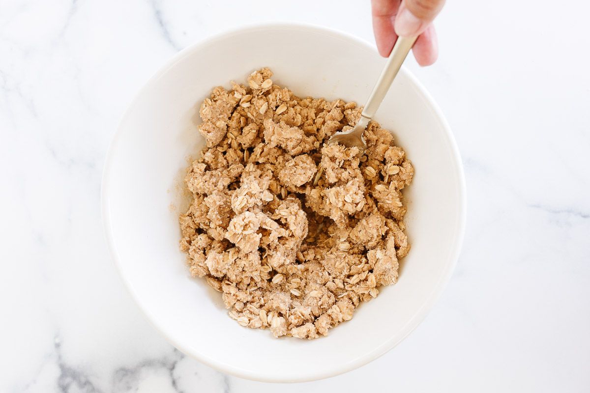 A small bowl full of a crumble topping with oats, prior to being baked on top of a dessert.