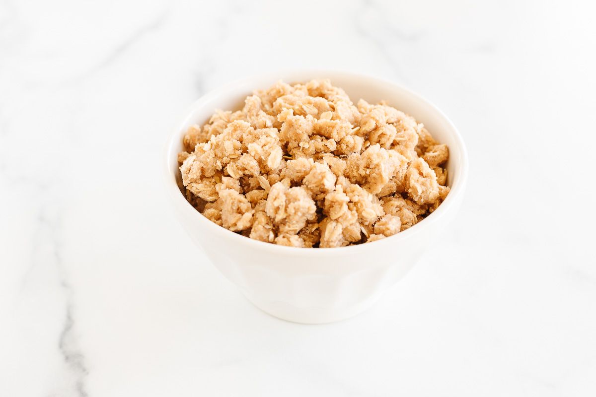 A small bowl full of a crumble topping with oats, prior to being baked on top of a dessert.