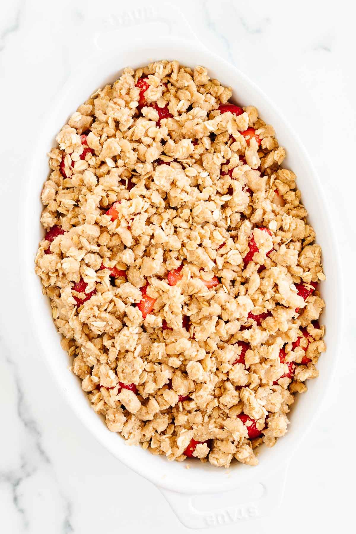 A crumble topping with oats on a strawberry crumble dessert, prior to baking.