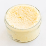 Garlic paste in a small clear glass jar, on a marble surface.