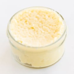 Garlic paste in a small clear glass jar, on a marble surface.