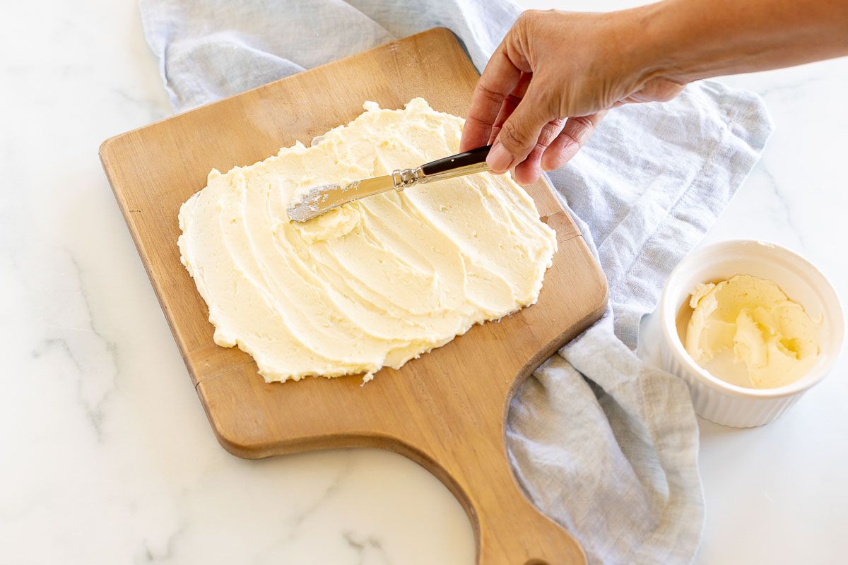 The beginning of a butter board, with a blue linen towel in the background