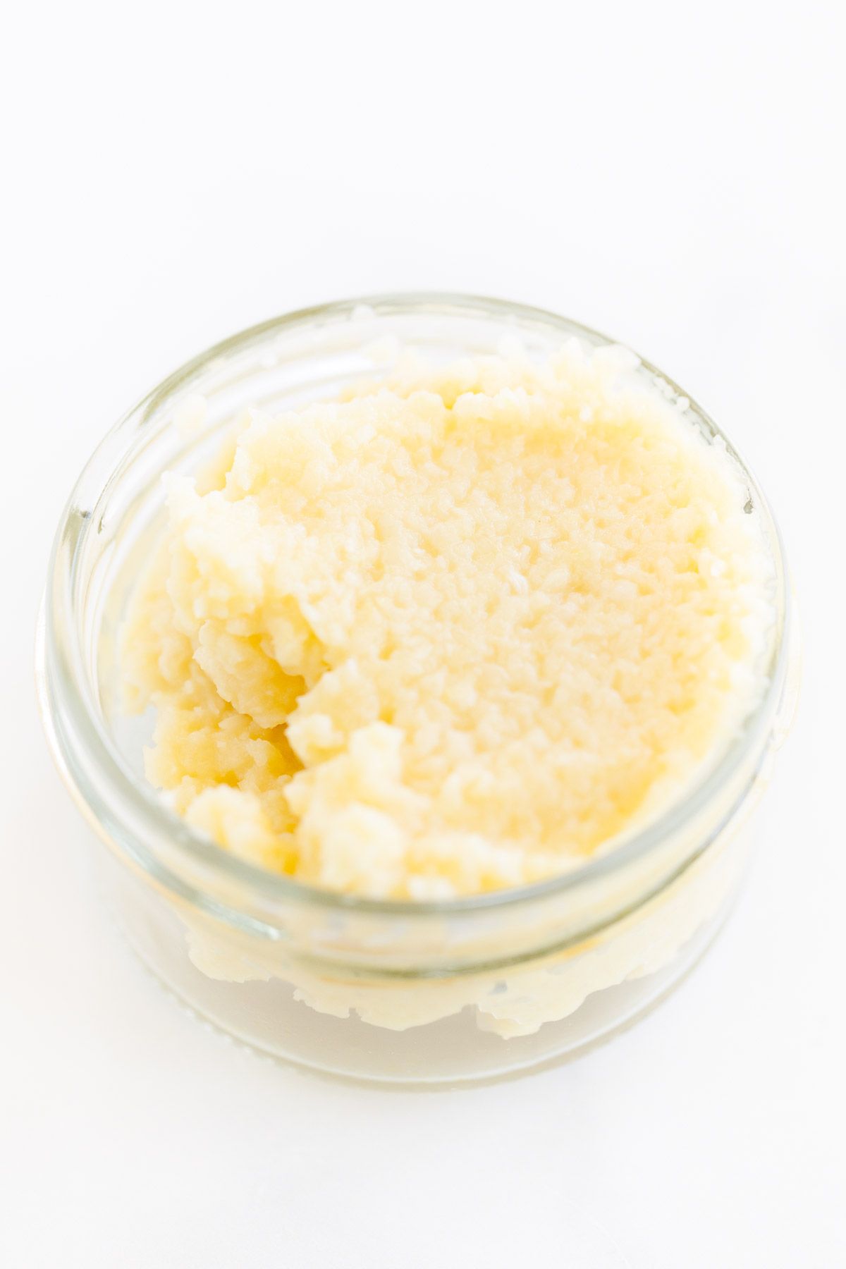 Garlic paste in a small clear glass jar, on a marble surface.