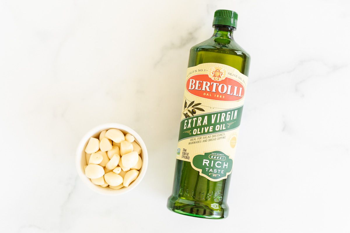 A small bowl of garlic cloves and a bottle of olive oil.