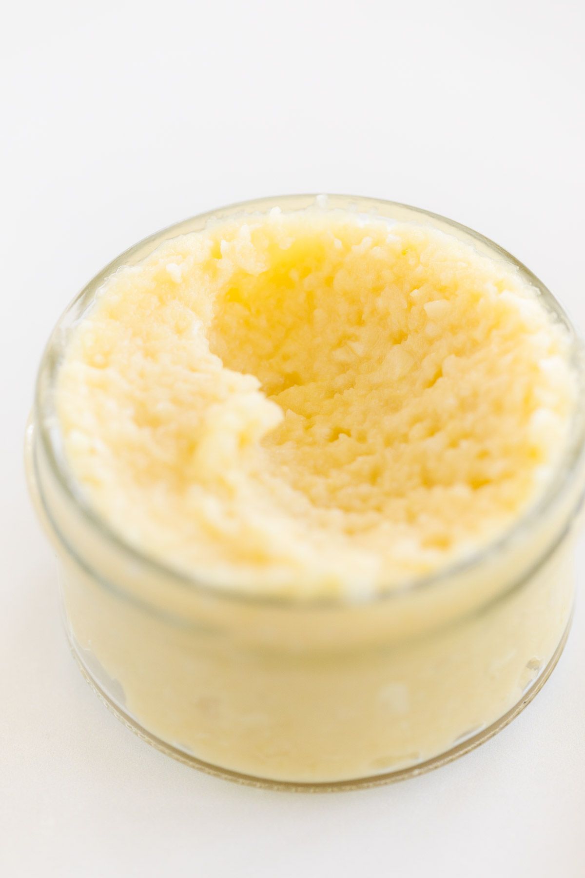 Garlic paste in a small clear glass jar, on a marble surface.