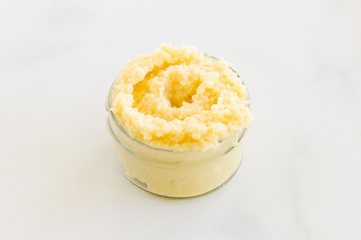 Garlic paste in a small clear glass jar, on a marble surface.