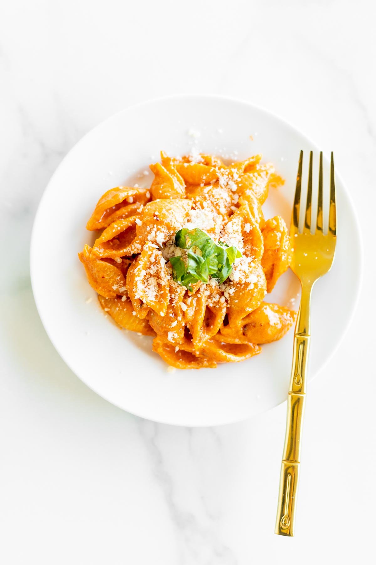 A white plate full of Gigi Hadid pasta (a vodka pasta recipe) with a gold fork.