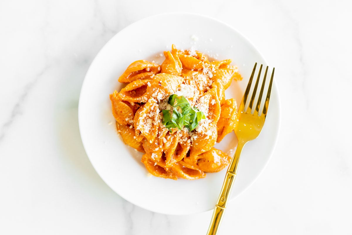 A white plate full of Gigi Hadid pasta (a vodka pasta recipe) with a gold fork.