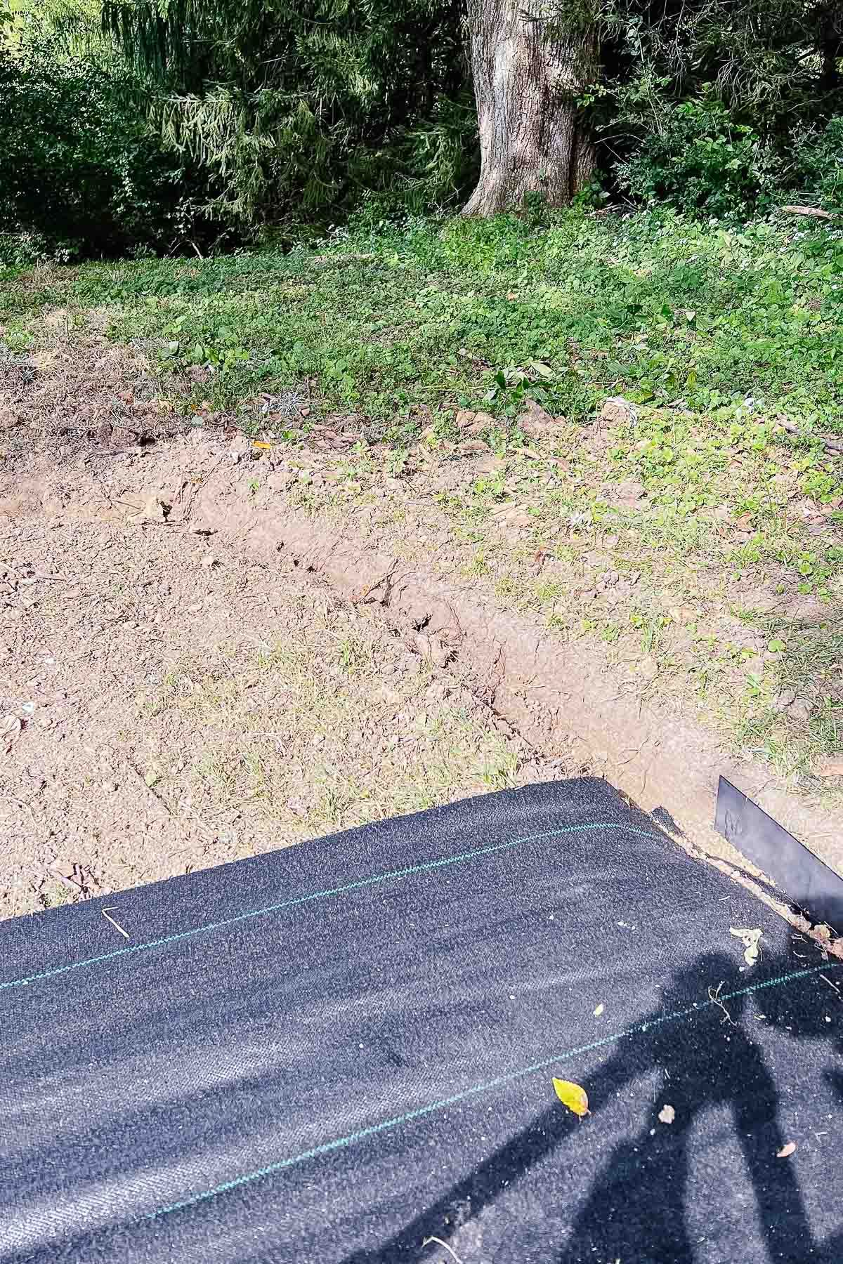 A fire pit patio in the process of being installed, with landscaping fabric laid out