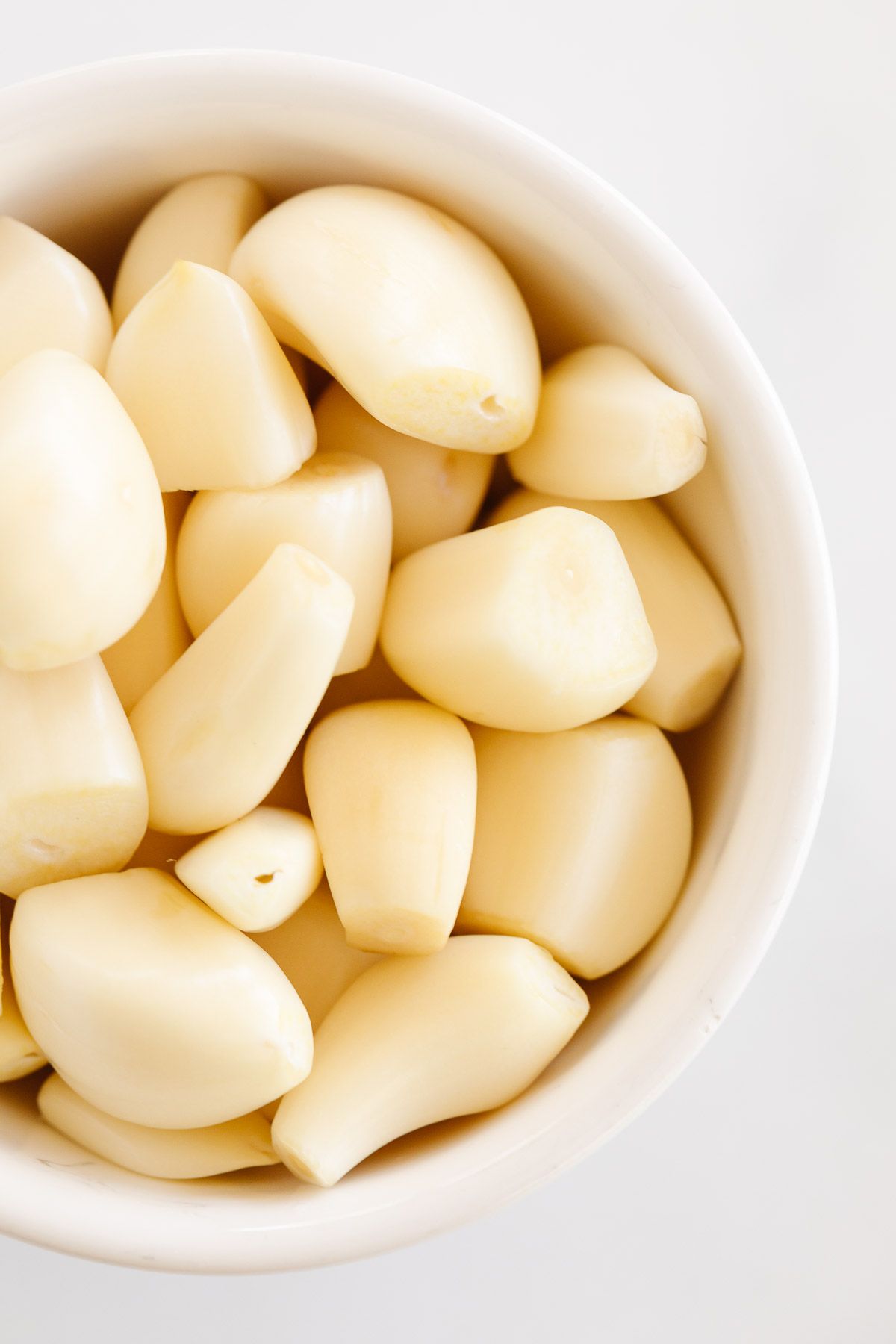 Peeled garlic cloves in a white bowl