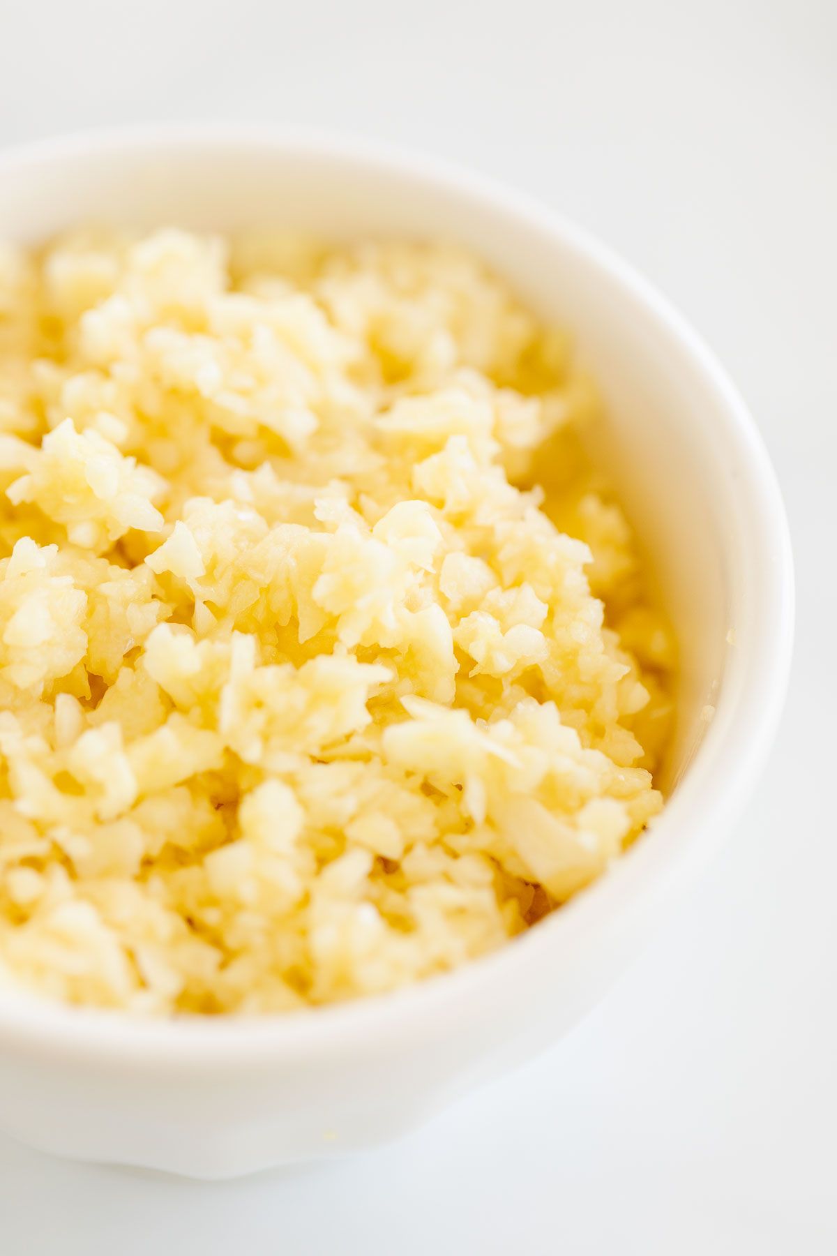 A close up of minced garlic in a white bowl.