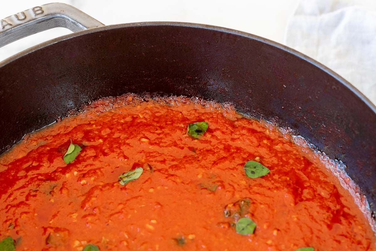 San Marzano tomato sauce in a cast iron pan, topped with chopped herbs.