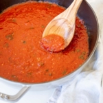 San Marzano Tomato Sauce in a gray cast iron pan, with a wooden spoon.