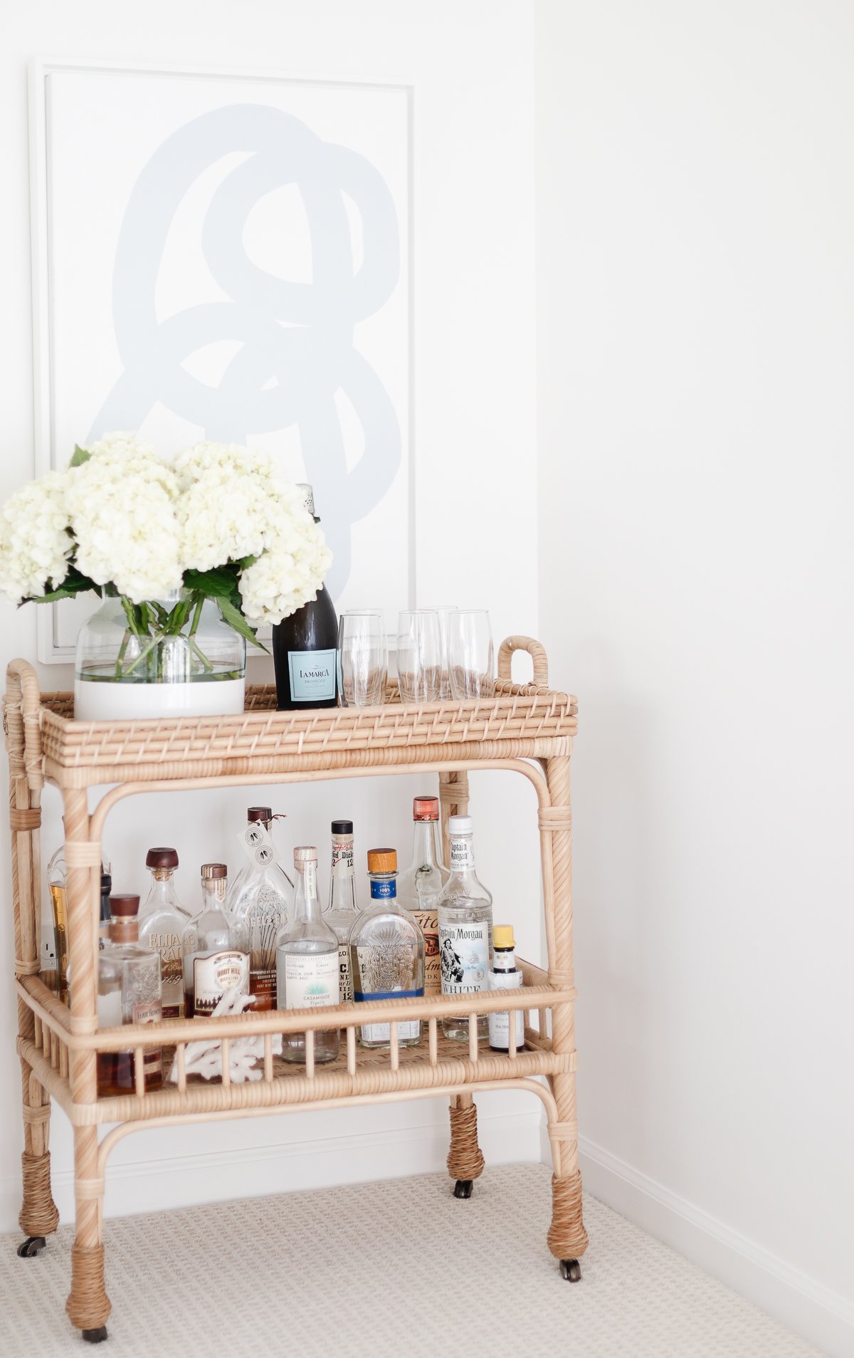 rattan bar cart with blue and white art over